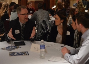 Students, GVSU Alumni are discussing their resumes at a table (photo).